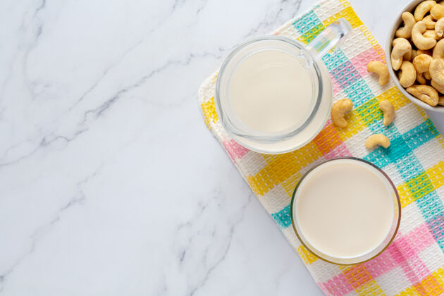 牛奶纯素腰果牛奶和腰果在大理石背景玻璃美味光桌子