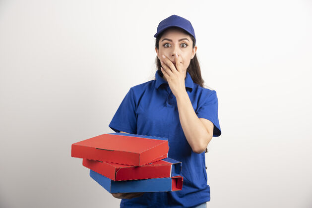 披萨年轻的女信使拿着一纸板披萨和剪贴板女人帽子工作