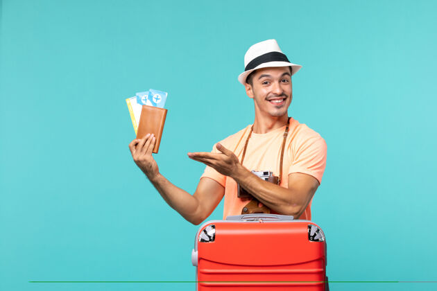 人正面图：男人在度假 手里拿着他的票 脸上挂着蓝色的微笑航行持有假期