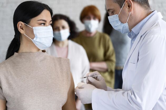 女人医生用医用口罩注射疫苗的女人乳胶手套预防医疗