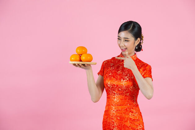 空美丽的亚洲女人开心地微笑着 手里拿着粉红背景的新鲜橘子过年中国文化女性
