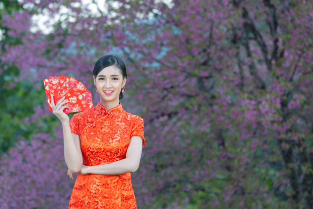 年轻美丽的亚洲女人在中国的新年里展示一些东西和拿红包信封展示问候语