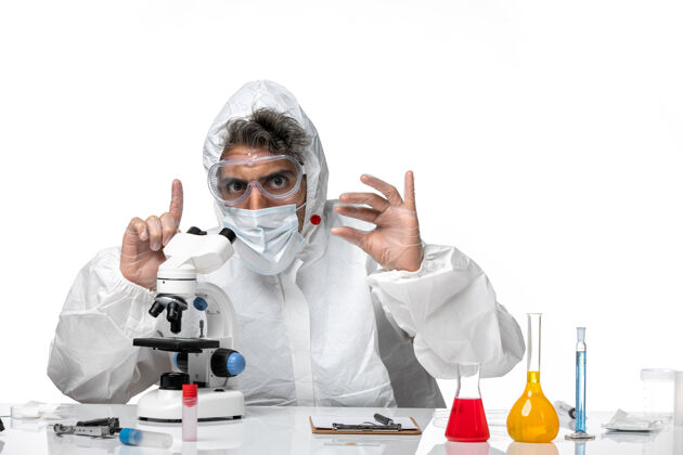 实验室男医生穿着防护服 戴着无菌口罩 用显微镜在白色皮肤上观察大流行病毒男医生