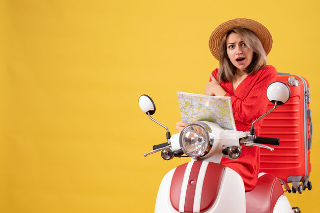时尚骑着轻便摩托车的漂亮女孩拿着红色手提箱拿着地图汽车地图摩托车