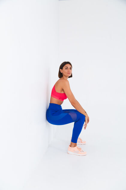 举重适合晒成棕褐色的运动型女人 腹肌 健身曲线 穿着上衣和蓝色紧身裤在白色椅子上锻炼时尚形状训练