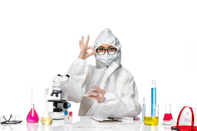 工作前视图穿着特殊防护服的年轻女化学家在白色地板上用显微镜工作病毒实验室covid-健康化学专业化学医学
