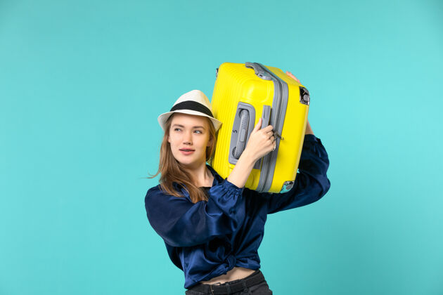 包前视：年轻女子在度假 拿着一个大袋子在淡蓝色的书桌上旅行 海上旅行抱工作年轻女子