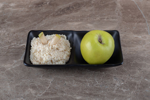 年糕磨碎的年糕和苹果在碗里 在大理石表面大米面筋面粉