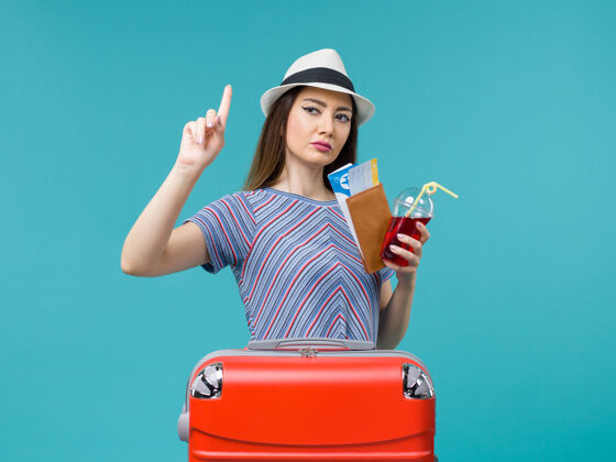 票前景：度假中的女人拿着果汁 拿着蓝色背景的机票 远航中的女子海上避暑飞机之旅航程举行旅程