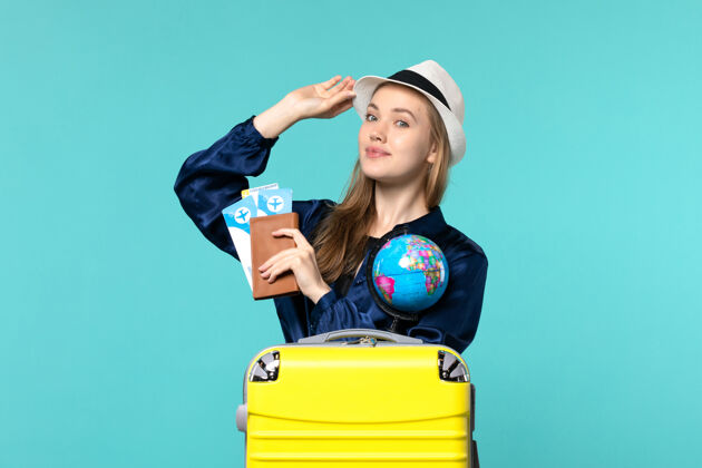 钱包正面图年轻女子拿着钱包拿着蓝色背景的机票远航女子远航海上度假年轻的女人票旅程