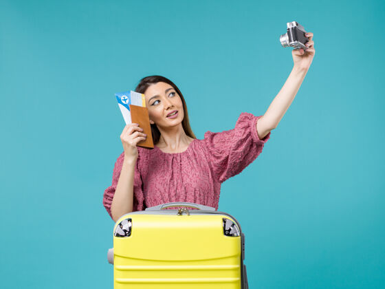微笑前景年轻女子手持相机在淡蓝色的背景下旅行度假女子远洋拍照浅蓝色年轻女子人物