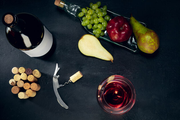 黑暗一瓶和一杯红酒 深色的石头表面有水果广告布里开胃酒