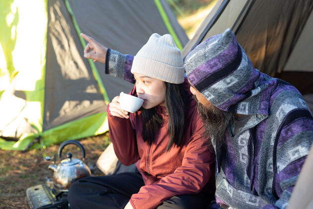 旅行者一对年轻夫妇早上坐在帐篷里喝咖啡探索女人饮酒
