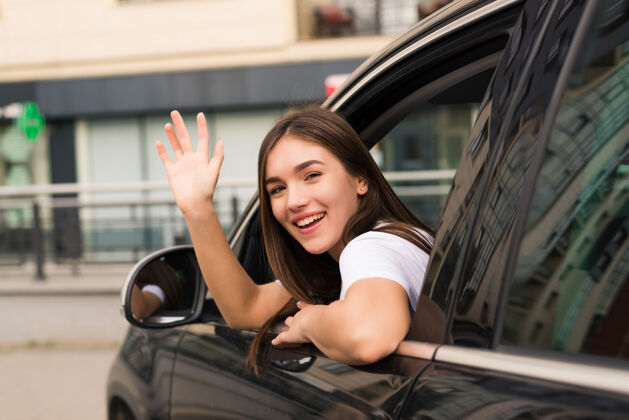微笑女司机在街上挥手告别告别滴镜子