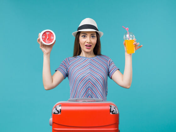 举行前景度假中的女人手持果汁和钟表在淡蓝色的背景下航行度假海上旅行微笑航行重量