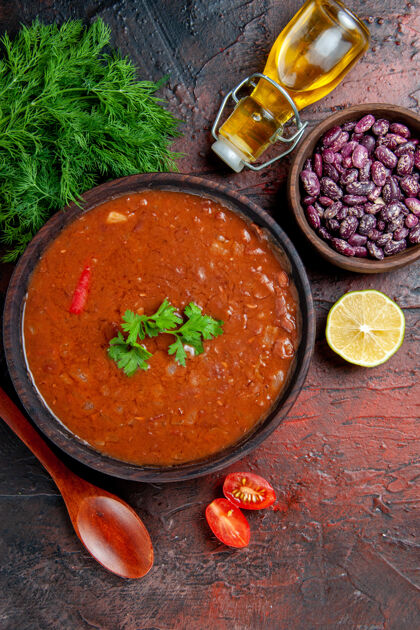 餐经典番茄汤的垂直视图在一个棕色的碗里豆子和勺子一瓶油餐厅食物西红柿汤