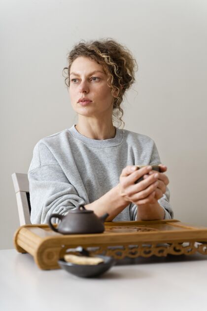 心灵一个卷发金发女人喝茶放松的正面图室内休闲室内活动