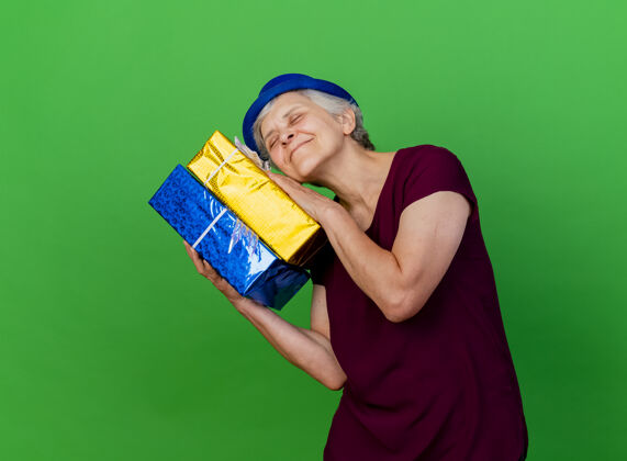 帽子高兴的老太太戴着聚会帽拿着礼品盒上了绿色礼物请聚会
