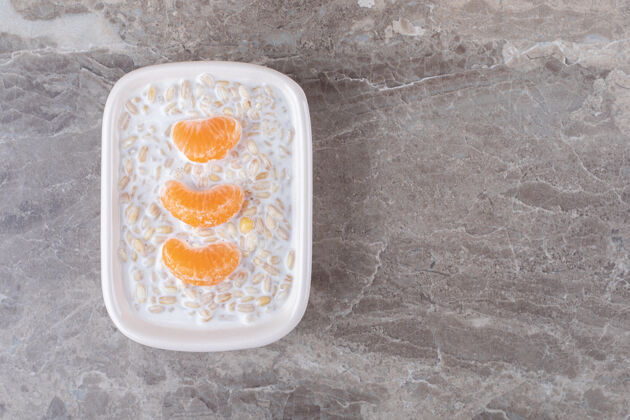 牙粉把橙子片放在碗里的粥上面 放在大理石表面天然碗风味