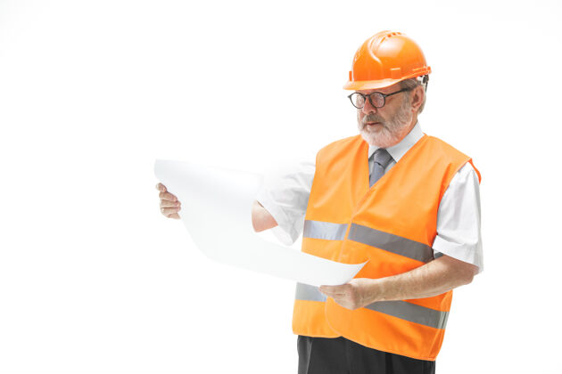 头盔穿着建筑背心和橙色头盔的建筑工人站在白色的工作室墙上建筑师安全帽现代