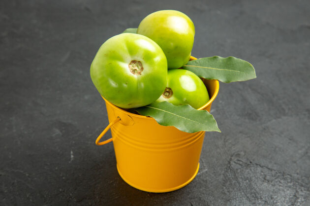 背景前视图绿色番茄桶和月桂叶在黑暗的背景健康深色果汁
