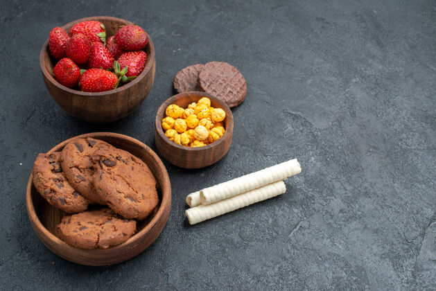 玉米前视图新鲜的红色草莓和甜饼干在黑暗的背景甜点早餐零食
