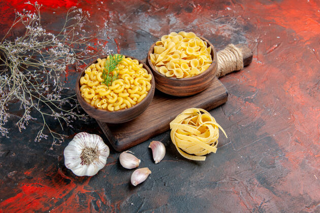 蔬菜木砧板上的各种生面食和混合色背景上的大蒜的俯视图晚餐午餐美味