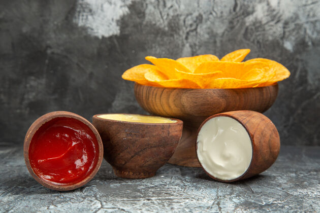 蛋黄酱灰色桌子上装饰着花形蛋黄酱和番茄酱的脆皮薯片俯视图薯片水果番茄酱