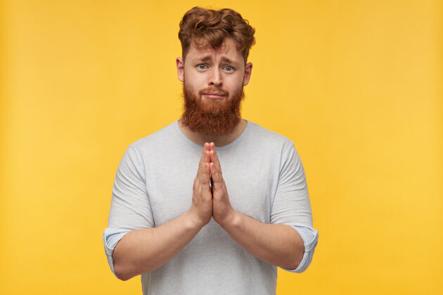 发型年轻悲伤的男性肖像 红色头发 大胡子 双手合十做祈祷的姿势 感觉被拥抱 请穿黄色衣服的人红发时尚模特