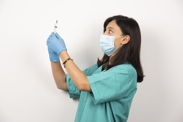 药品年轻医生戴着医用面罩和手套 手持白色背景的注射器高质量照片医生疫苗注射