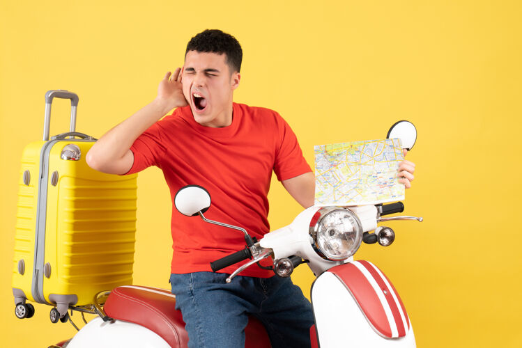 旅行正面图年轻人穿着休闲服坐在轻便摩托车上拿着旅游地图听着什么地图年轻人视图