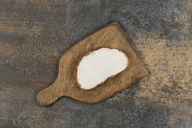 奶油在木板上放一片烤面包和酸奶油切片美味酸奶油
