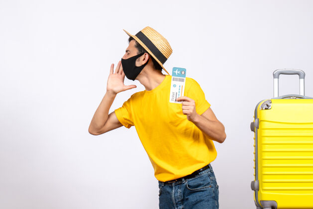 稻草正面图：一个戴草帽的年轻人站在黄色手提箱旁 手里拿着旅行票在叫什么男人视图站立