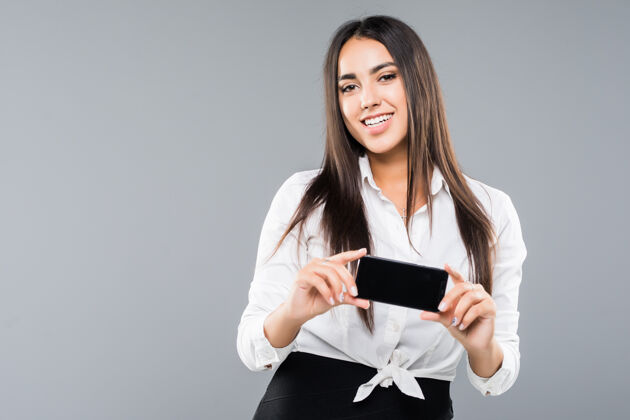 女人一个兴奋的年轻女商人指着白屏手机的肖像年轻人工作手机