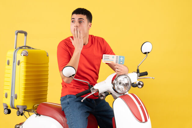 主动正面图：一个穿着便服的年轻男子拿着车票坐在轻便摩托车上男持有视图