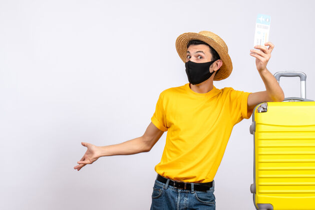 前面正面图穿着黄色t恤的年轻人站在黄色手提箱旁举着机票T恤微笑衬衫