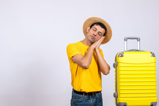 年轻游客正面图年轻的游客站在黄色的手提箱旁睡觉人视图黄色