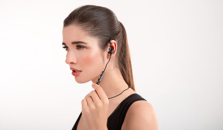 耳机穿着黑色上衣慢跑的黑发女人戴着耳机听音乐摆着灰色的姿势运动装耳机肖像