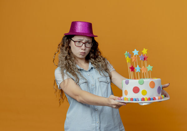 眼镜戴着眼镜和粉色帽子的未出嫁的年轻女孩在一旁拿着生日蛋糕蛋糕持有女孩