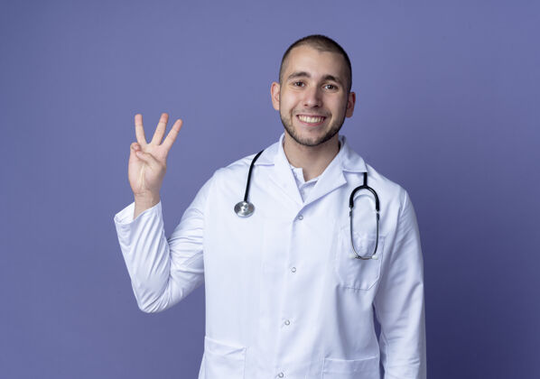 年轻面带微笑的年轻男医生 身穿医用长袍 脖子上戴着听诊器 三只手被隔离在紫色的墙上姿势人感情