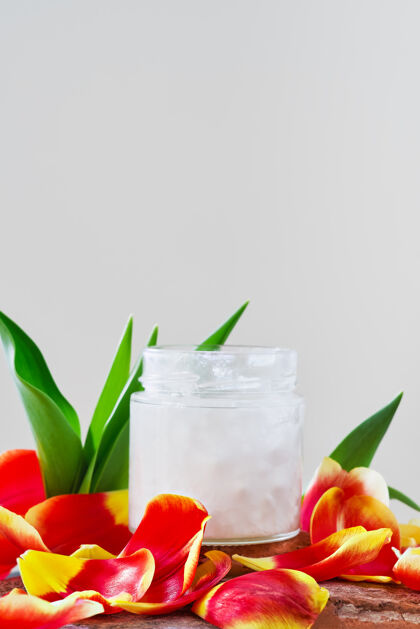 卫生椰子油在白色的罐子里被郁金香花瓣包围 特写有临摹空间芳香疗法心灵身体