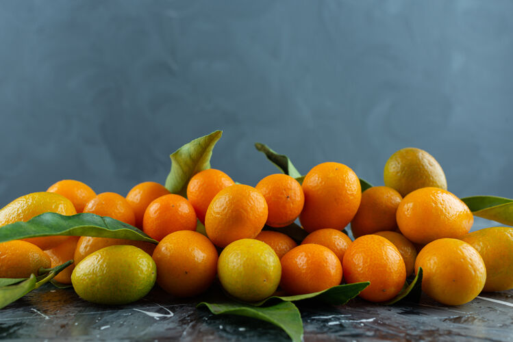 明亮一堆成熟的金橘 大理石表面有绿叶柑橘金橘金橘