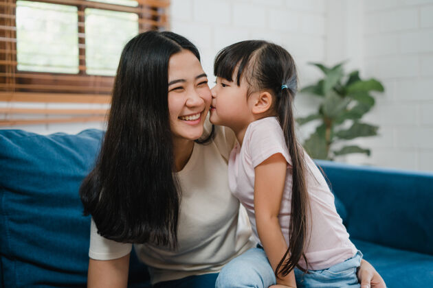 礼物快乐的亚洲家庭妈妈和女儿在家里拥抱亲吻脸颊祝贺生日母亲爱情感