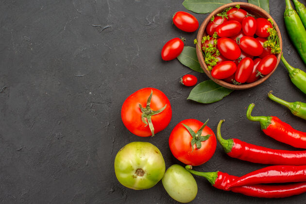 饮食顶视图一碗樱桃西红柿 红色和绿色的辣椒 以及黑色背景上的西红柿甜椒新鲜素食