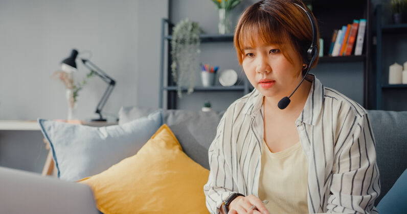 通信亚洲女商人在起居室用笔记本电脑与同事谈论视频通话计划笔记本电脑沙发女性
