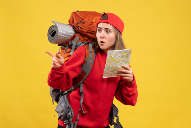 地图正面图漂亮的女旅行者 背包里拿着地图 指向左边成人指着背包