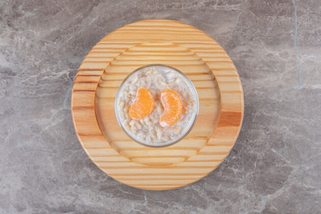 橙子在大理石背景上 在木盘上的玻璃杯里放两片橙子粥碗美味风味