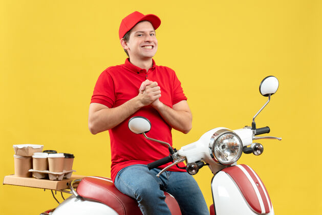 命令顶视图的快乐满意的年轻人穿着红色衬衫和帽子在黄色背景下传递命令黄色背景摩托车