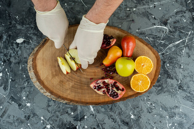 切男性手戴手套在大理石桌上切新鲜苹果准备刀水果