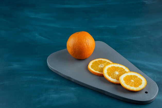 异国情调在蓝色的表面上放着切成片的多汁橙子的木板柑橘新鲜水果